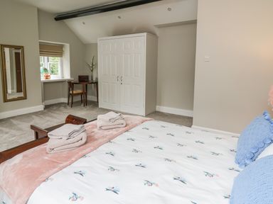 A bedroom with a bed with bird patterned bedding towels on a blanket a white wardrobe a small round table with a chair and a mirror on the wall at Glamorgan House Cardiff