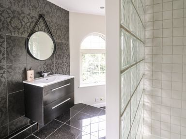 A bathroom with a black vanity sink mirror and frosted glass wall at Glamorgan House Cardiff