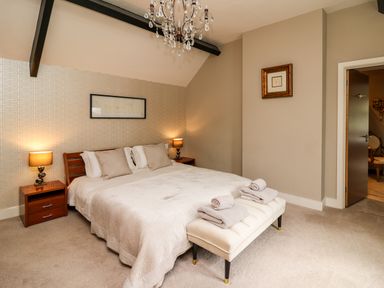 A bedroom with a double bed two bedside tables with lamps and a bench with folded towels at Glamorgan House Cardiff