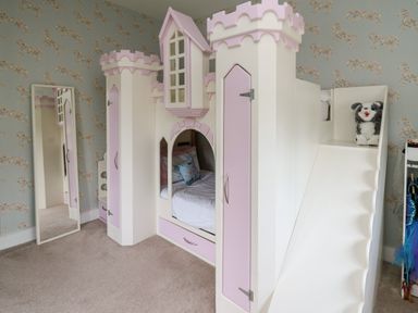 A children's bedroom with a castle-themed bed with a slide and a stuffed toy on it at Glamorgan House Cardiff