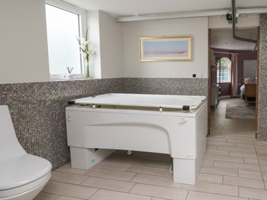A bathroom with a white bathtub next to a window and a toilet at Glamorgan House in Cardiff