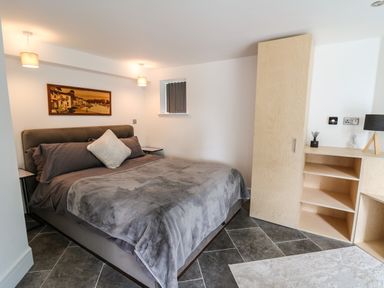 A bedroom with a double bed a wooden cabinet and shelves and a small window at Glamorgan House in Cardiff
