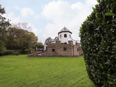 A large house with a stone lower wall and white upper walls surrounded by a lawn and trees at Glamorgan House in Cardiff