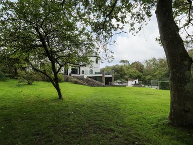 A grassy lawn with trees and a white house with stone steps in the background at Glamorgan House in Cardiff