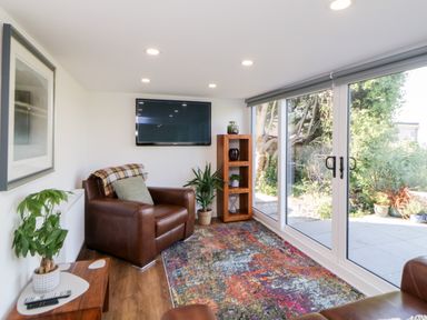 A living room with leather armchairs a colorful rug and large glass sliding doors at Riverview @ 1 Brunel View in Saltash
