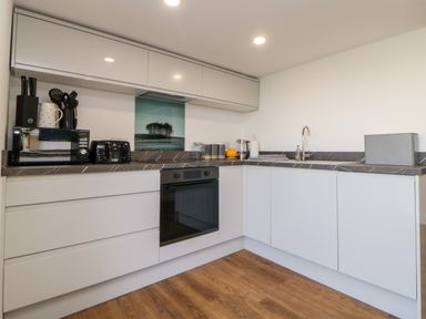 A kitchen with white cabinets brown countertops and wooden floor at Riverview @ 1 Brunel View in Saltash