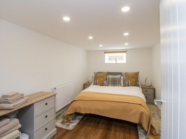 A bedroom with a double bed two bedside tables a small window and a chest of drawers at Riverview 1 Brunel View in Saltash