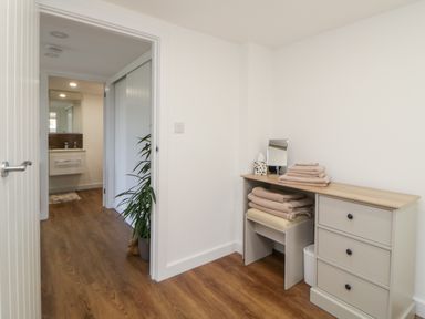 A room with a dresser and folded towels next to a hallway with a plant and bathroom at Riverview @ 1 Brunel View in Saltash