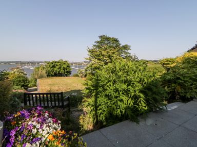 A garden with colorful flowers a bench and a lawn overlooking boats on water at Riverview 1 Brunel View in Saltash