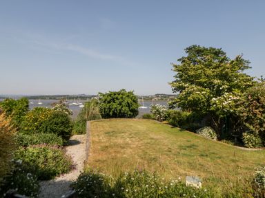 A garden with grass lawn and trees overlooking a river with boats at Riverview @ 1 Brunel View in Saltash