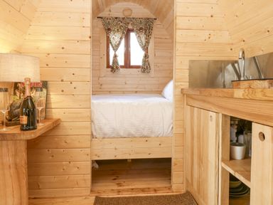 A small wooden room with a bed in the alcove and a kitchenette with a sink and a wooden counter at The Leveret in Eppleby
