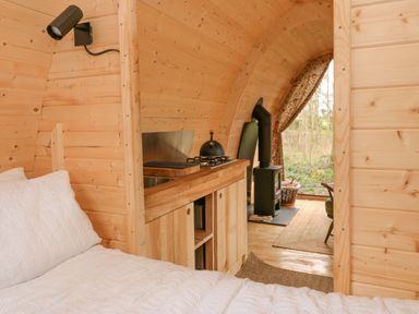 A small wooden cabin interior with a bed a kitchenette and a wood stove at The Leveret in Eppleby