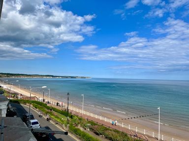 A coastal road with parked cars and people walking along a promenade by the beach at Apartment 9 Beaconsfield House in Bridlington