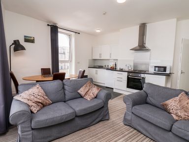 A living room with two sofas and a dining table near a kitchen at 7 Beach View Beaconsfield House in Bridlington