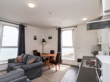 A living room with two sofas a dining table with four chairs and a kitchen area at 7 Beach View Beaconsfield House in Bridlington