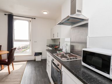 A kitchen with a stove microwave and dining table near a window at 7 Beach View Beaconsfield House in Bridlington