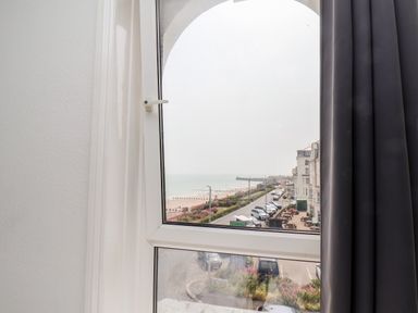 A window view overlooking a coastal road with parked cars and buildings near the beach at 7 Beach View @ Beaconsfield House in Bridlington