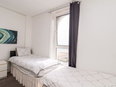 A bedroom with two single beds next to a window with a view of the beach at 7 Beach View Beaconsfield House in Bridlington