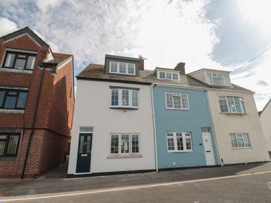 A street view of attached houses with white and blue facades and multiple windows at Quay Cottage Sea View in Poole