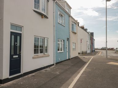 A street with a row of houses in white and blue near the sea at Quay Cottage Sea View in Poole