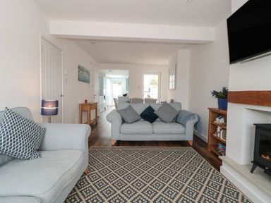 A living room with two sofas a patterned rug a wall-mounted TV and a fireplace at Quay Cottage - Sea View in Poole