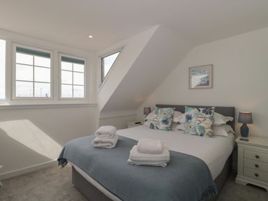 A bedroom with a bed lamp bedside tables and windows at Quay Cottage - Sea View in Poole
