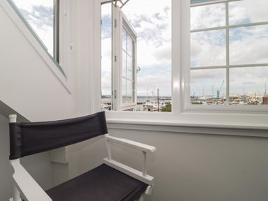 A chair next to a window with a view of a marina at Quay Cottage - Sea View in Poole