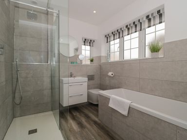 A bathroom with a shower enclosure bathtub sink toilet and windows with striped blinds at Quay Cottage - Sea View in Poole