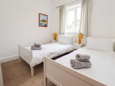 A bedroom with two single beds white bedding and folded towels on the beds at 1 Orchard Cottages in Dunstan near Craster