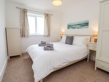 A bedroom with a double bed with white bedding and folded towels on the bed at 1 Orchard Cottages in Dunstan near Craster