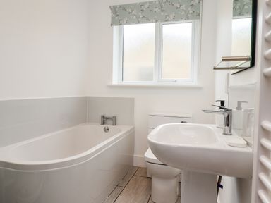 A bathroom with a bathtub sink toilet and window at 1 Orchard Cottages Dunstan near Craster