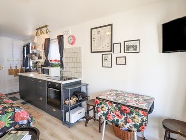 A kitchen area with black cabinets a microwave oven and a floral table with stools at Creed Cabin in Stornoway