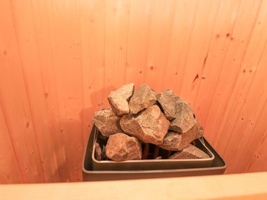 A sauna heater with stones inside a wooden sauna at Creed Cabin in Stornoway
