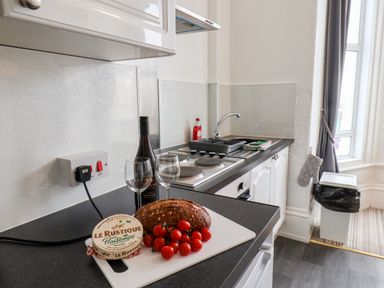 A kitchen counter with bread cherry tomatoes cheese wine glasses and a bottle of wine in 4 Beach View Beaconsfield House Bridlington