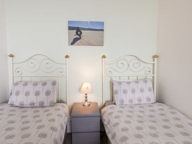 A bedroom with two single beds a nightstand with a lamp and a wall picture at 4 Beach View Beaconsfield House in Bridlington