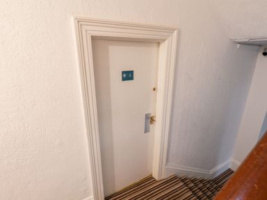 A closed white door with the number 4 on it at the bottom of striped carpeted stairs