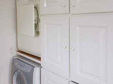 A laundry area with a stacked washer and dryer and white cabinets at Meeligolleen in Coill Tra