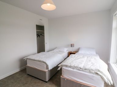 A bedroom with two single beds a nightstand with a lamp and an open closet at Meeligolleen in Coill Tra