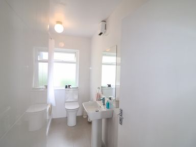 A bathroom with a toilet sink mirror and window at Meeligolleen in Coill Tra