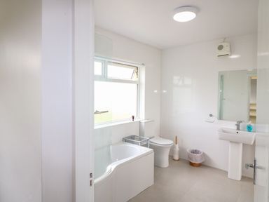 A bathroom with a bathtub toilet sink mirror and window at Meeligolleen in Coill Tra