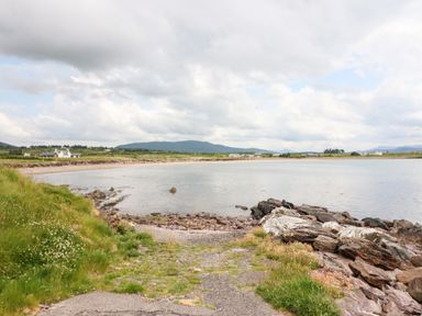 A rocky shoreline with grass and water at Meeligolleen in Coill Tra