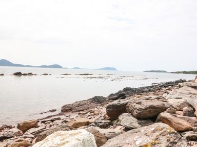 A rocky shoreline with water and distant islands at Meeligolleen in Coill Tra