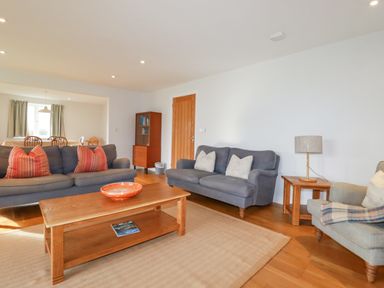 A living room with two grey sofas a wooden coffee table a side table with a lamp and a chair at Freefolk Polzeath
