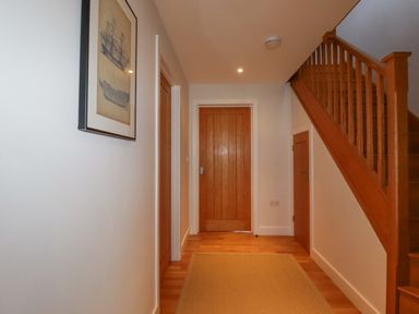 A hallway with wooden doors and staircase and a framed picture on the wall at Freefolk in Polzeath