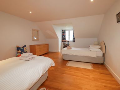 A bedroom with two single beds a wooden dresser and a window with curtains at Freefolk in Polzeath