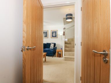 A living room with a blue sofa a wooden coffee table side table staircase and two framed pictures on the wall at The Mill Stones in Stalham
