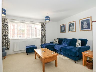 A living room with a blue sofa wooden coffee table and framed pictures on the wall at The Mill Stones in Stalham