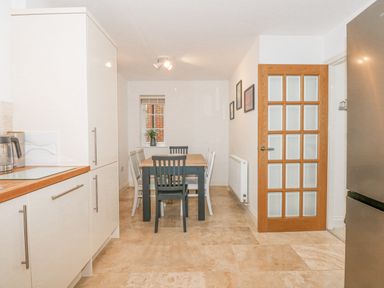 A kitchen with a dining table and chairs near a window and a glass paneled wooden door at The Mill Stones in Stalham
