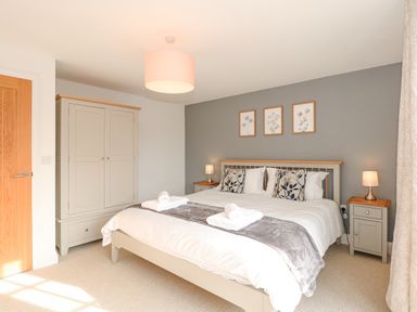 A bedroom with a double bed bedside tables lamps wardrobe and framed pictures at The Mill Stones in Stalham