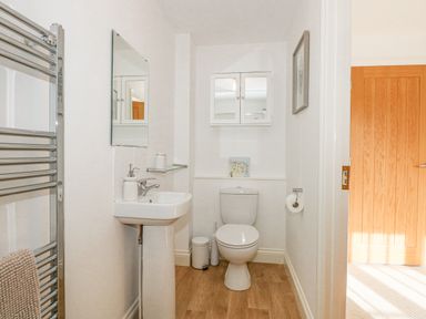 A bathroom with a toilet sink mirror and towel rack at The Mill Stones in Stalham
